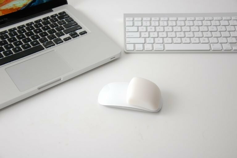 The Apple Magic Mouse with the MMFixed on it next to a macbook pro and an apple wireless keyboard